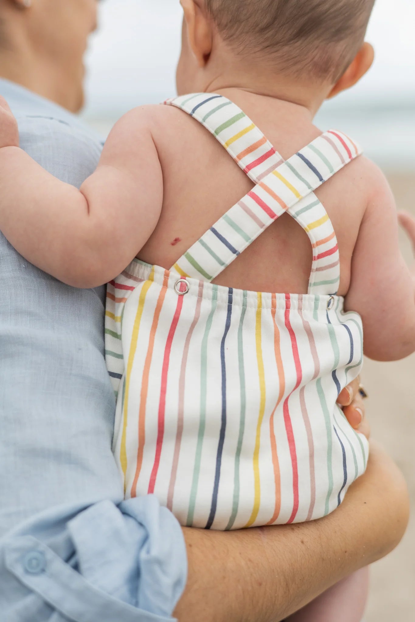 Pehr Stripes Away Rainbow Criss-Cross One-Piece with colorful rainbow stripes and criss-cross straps, suitable for infants or toddlers.