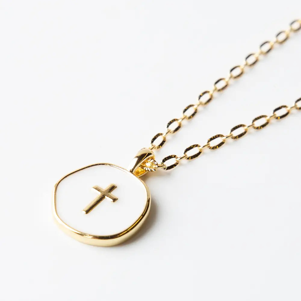White enamel cross pendant with faith over fear inscription on gold chain, by Lenny & Eva, shown close-up image.