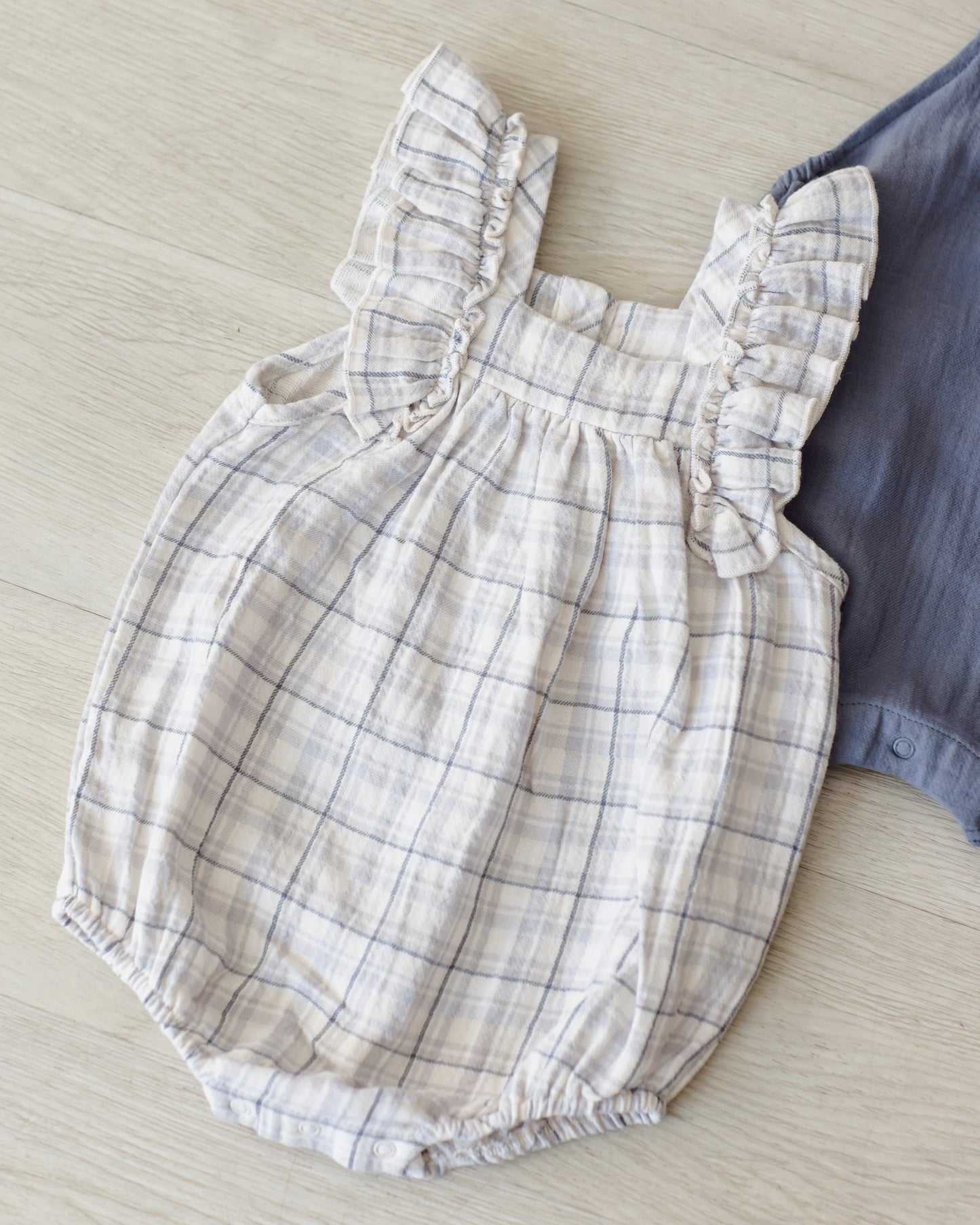 Blue plaid Quincy Mae Maya romper shown on a child, featuring short sleeves and a relaxed, comfortable fit in a casual lifestyle setting.