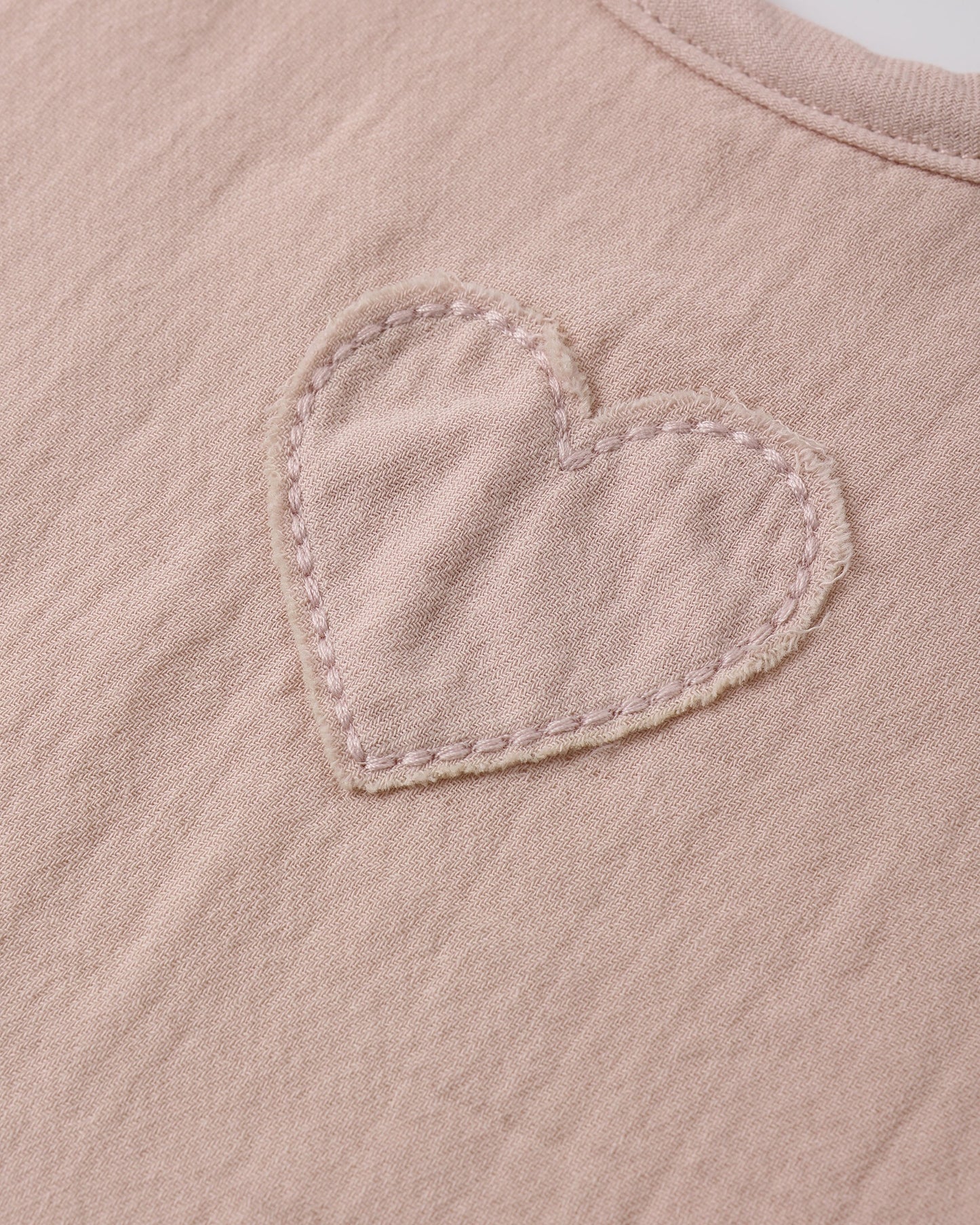 Close-up of Quincy Mae blush woven tie bib showing detailed fabric and delicate design for baby accessories.