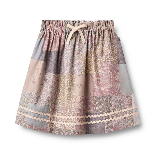 Wheat Patchwork Flowers Nya Skirt featuring colorful floral patchwork design and a relaxed fit, displayed on a hanger.