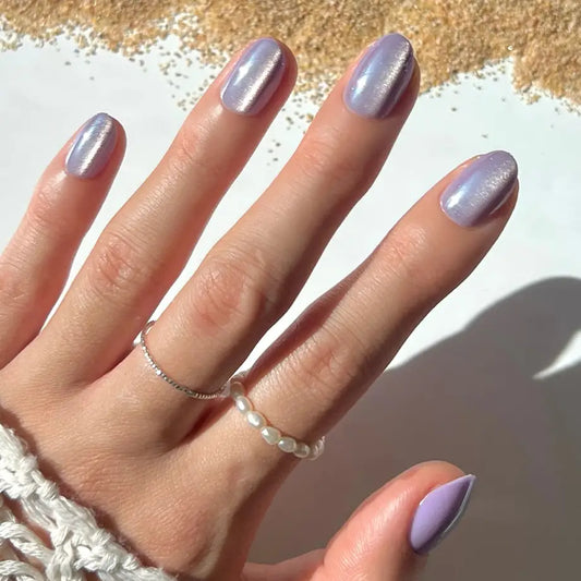 Short oval purple iridescent Mermaid's Tail press-on nails by Glamnetic displayed on a hand, showcasing their glossy, shimmering finish.
