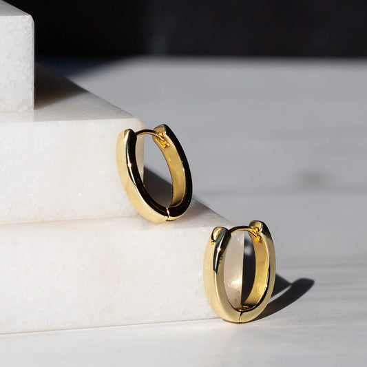 Lenny & Eva tarnish-resistant gold oval hoop earrings, shiny and sleek, hanging with a smooth oval shape and secure clasp.