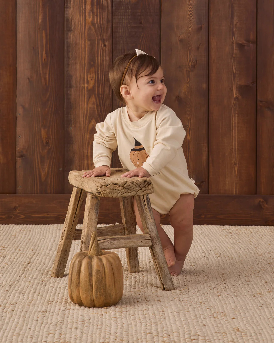 Baby girl wearing Quincy Mae Lil Pumpkin Crewneck Bubble Romper, soft orange and cream fabric, front view showing adorable pumpkin theme.