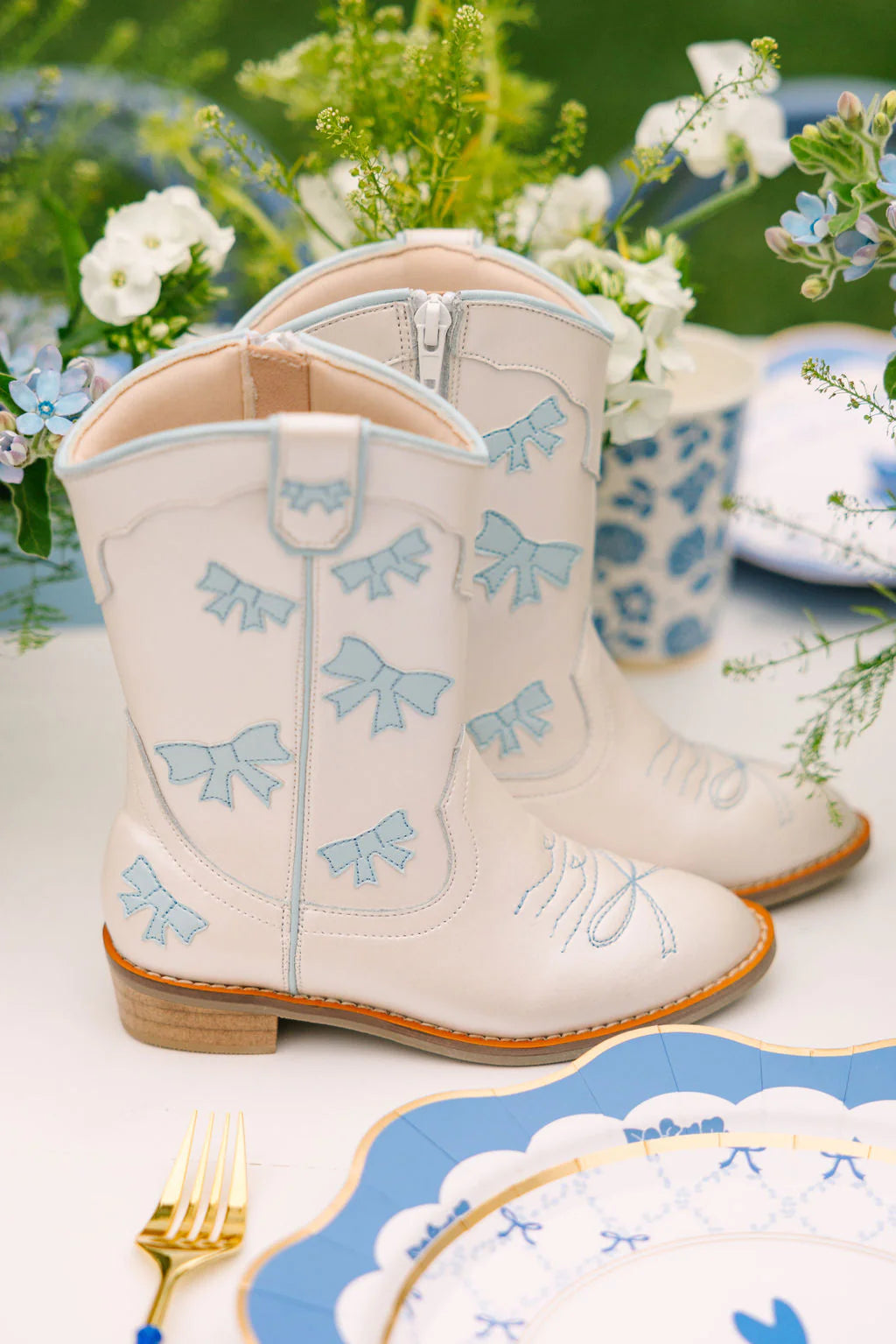 Wild + Rae cowgirl baby blue bow boots with decorative bows and stitching, stylish western-inspired footwear for kids.