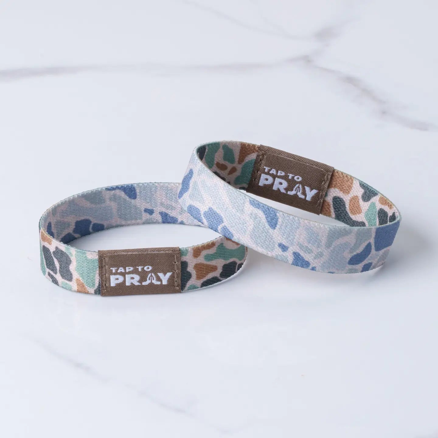Versible Tap To Pray™ wristbands in river rock camo and sage, featuring a classic design with prayer and faith symbols.