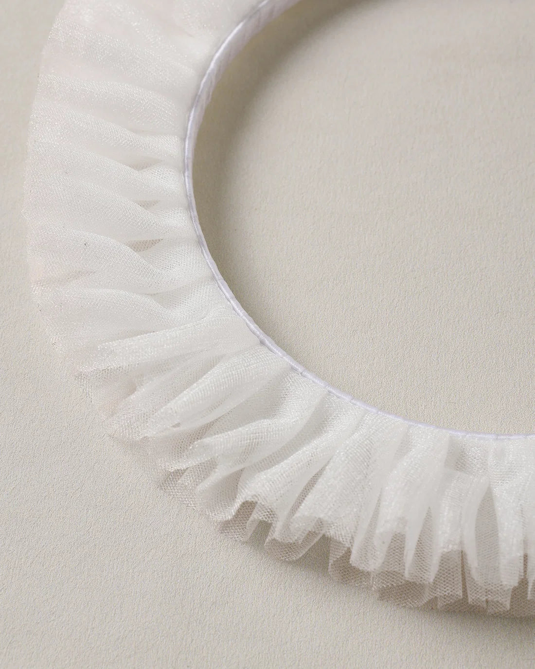 Ivory Noralee ruffle headband with soft fabric and decorative ruffles, perfect for adding a charming touch to any outfit.