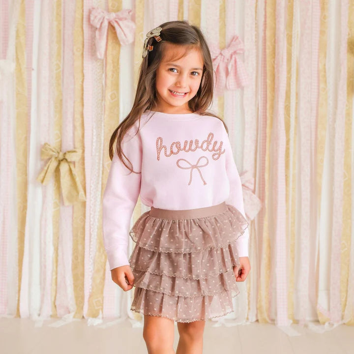 Model wearing Sweet Wink Howdy Darling Western Sweatshirt with cowgirl ruffle tutu skirt, western-themed casual outfit.