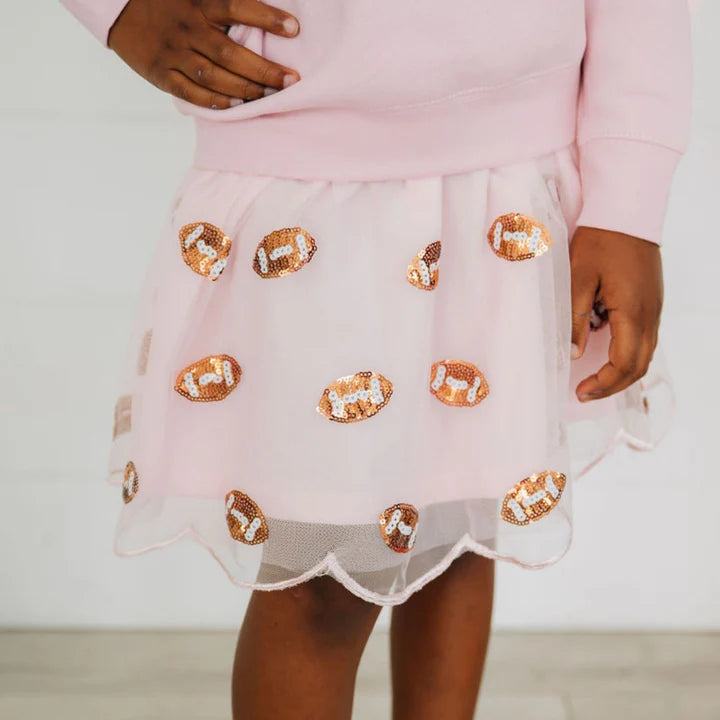 Model wearing a pink mini sequin footballs tutu skirt by Sweet Wink, featuring colorful footballs and a layered tulle design.