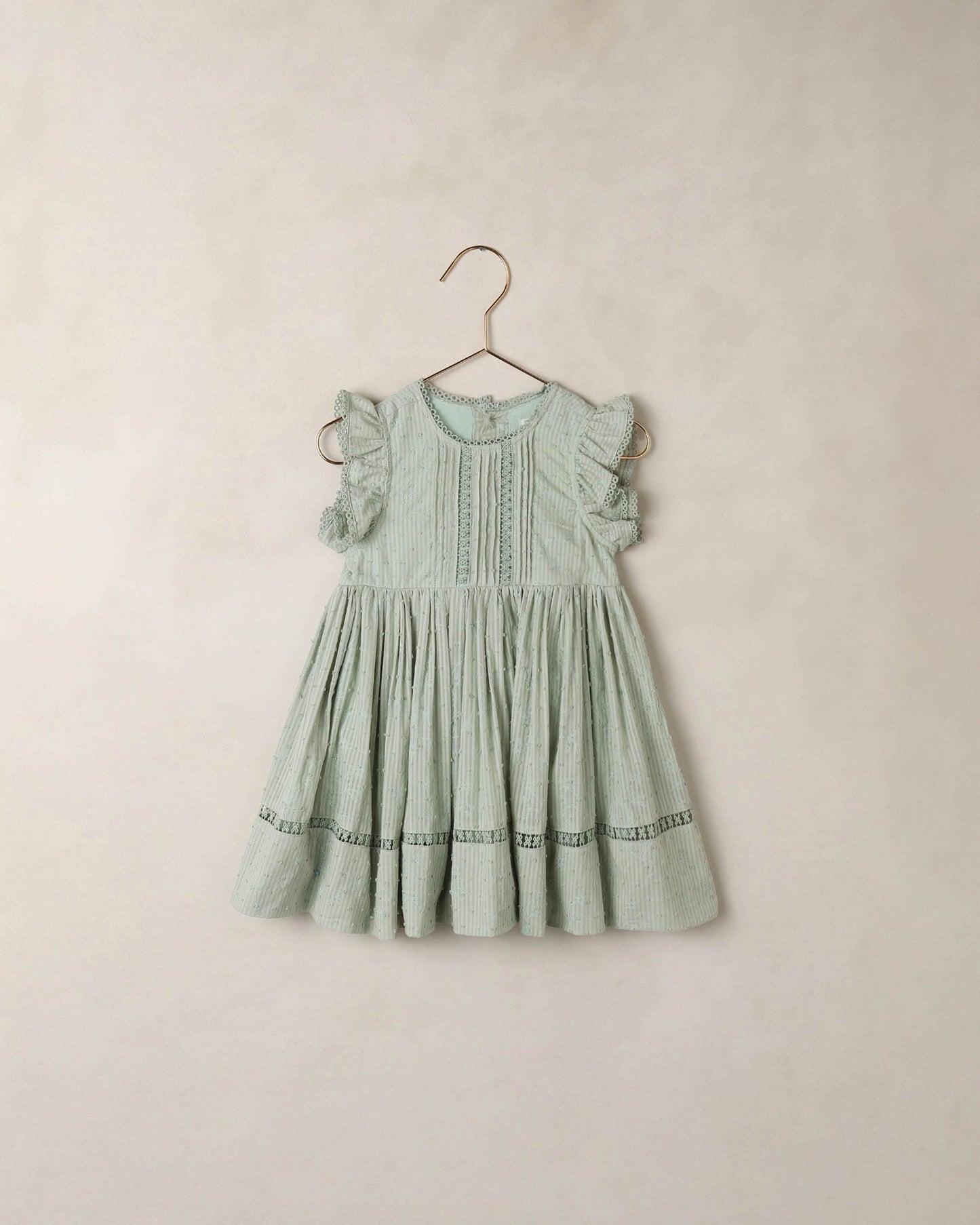Noralee Eucalyptus Isla Dress shown hanging on a wooden hanger with a flowy, lightweight fabric and botanical print.