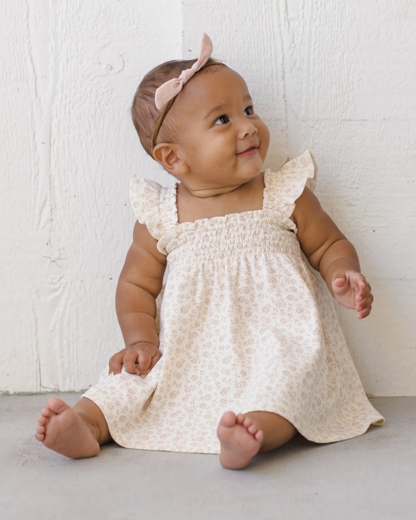 Quincy Mae Ditsy Smocked Jersey Dress in soft fabric, featuring smocking detail and a charming floral pattern, displayed in a lifestyle setting.