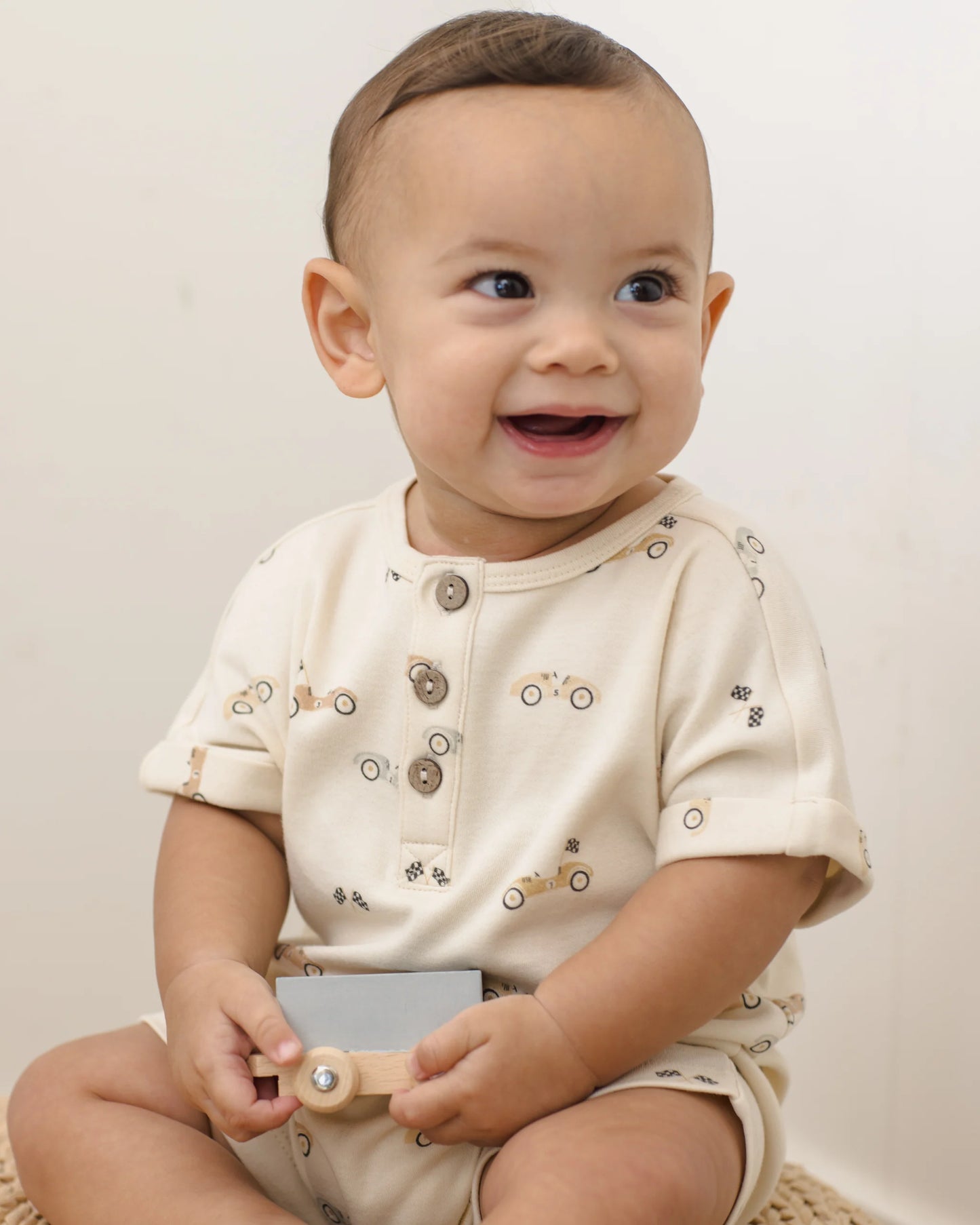 Quincy Mae race car short sleeve one-piece for babies, featuring a colorful race car print on soft fabric.