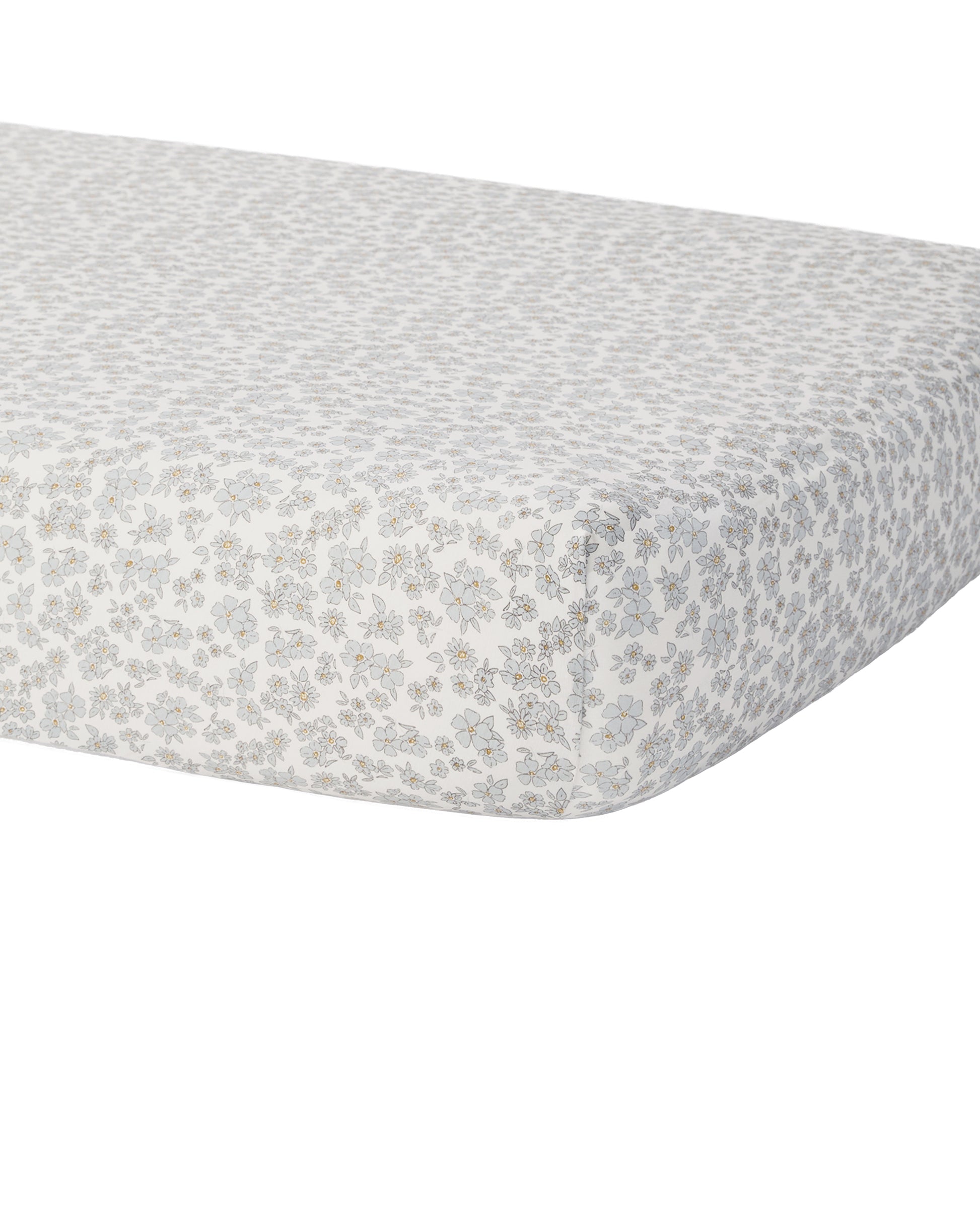 Blue floral bamboo crib sheet by Quincy Mae, showcasing soft fabric with a delicate floral print on a crib mattress.