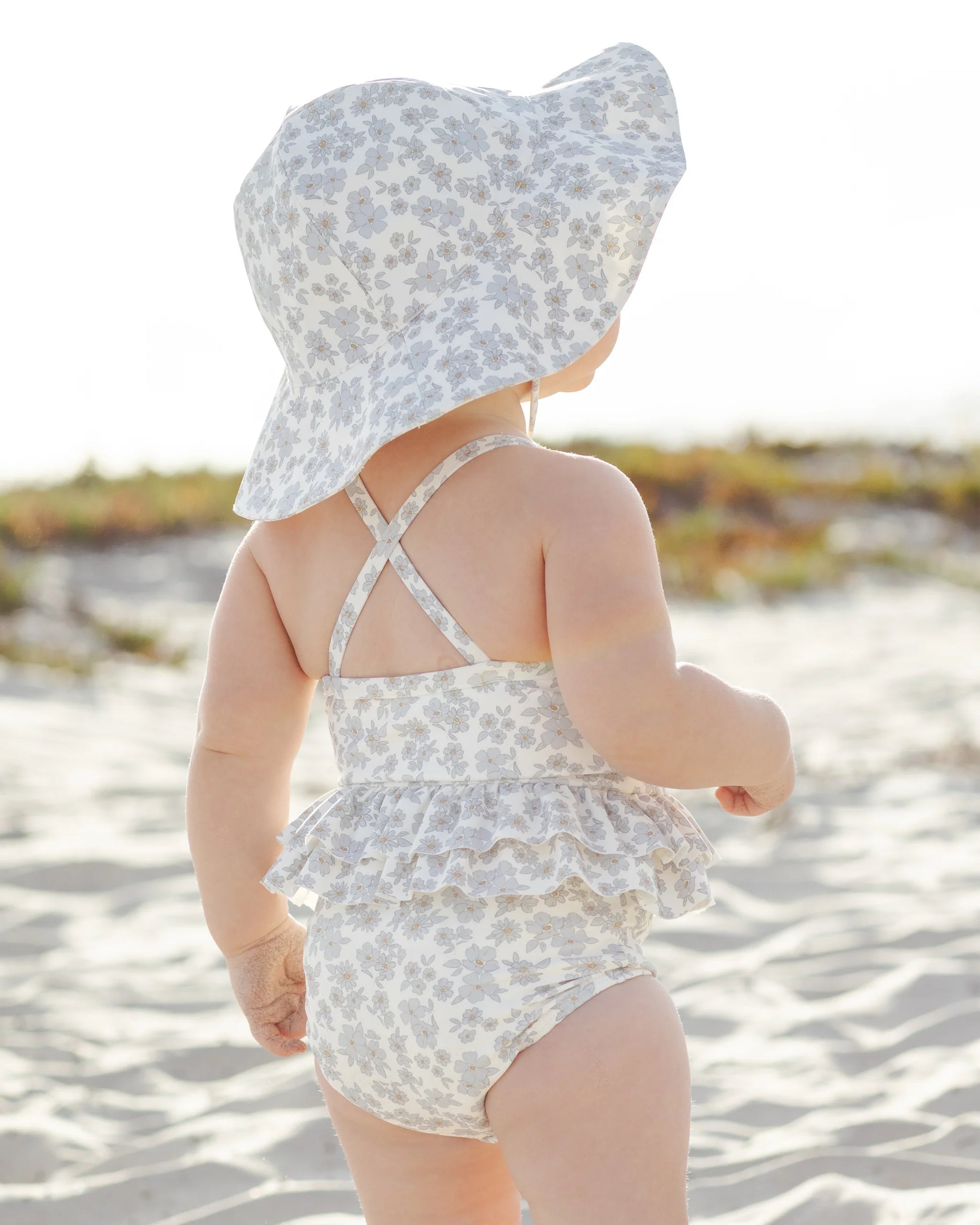 Blue floral ruffled one-piece swimsuit by Quincy Mae featuring a charming floral pattern and ruffled details.