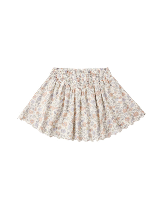 Ivory Bloom Smocked V Mini Skirt by Rylee & Cru worn on a model, featuring a smocked waistband and flowy fabric.