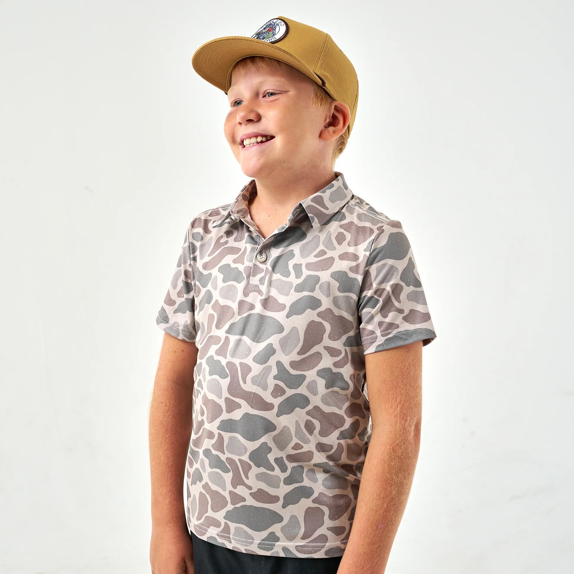 Youth classic deer camo performance polo by Burlebo, featuring a camouflage pattern and comfortable fit modeled on a young person.