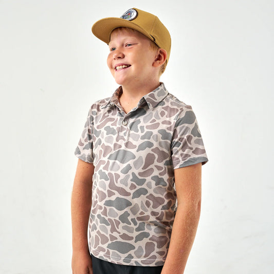 Youth classic deer camo performance polo by Burlebo, featuring a camouflage pattern and comfortable fit modeled on a young person.